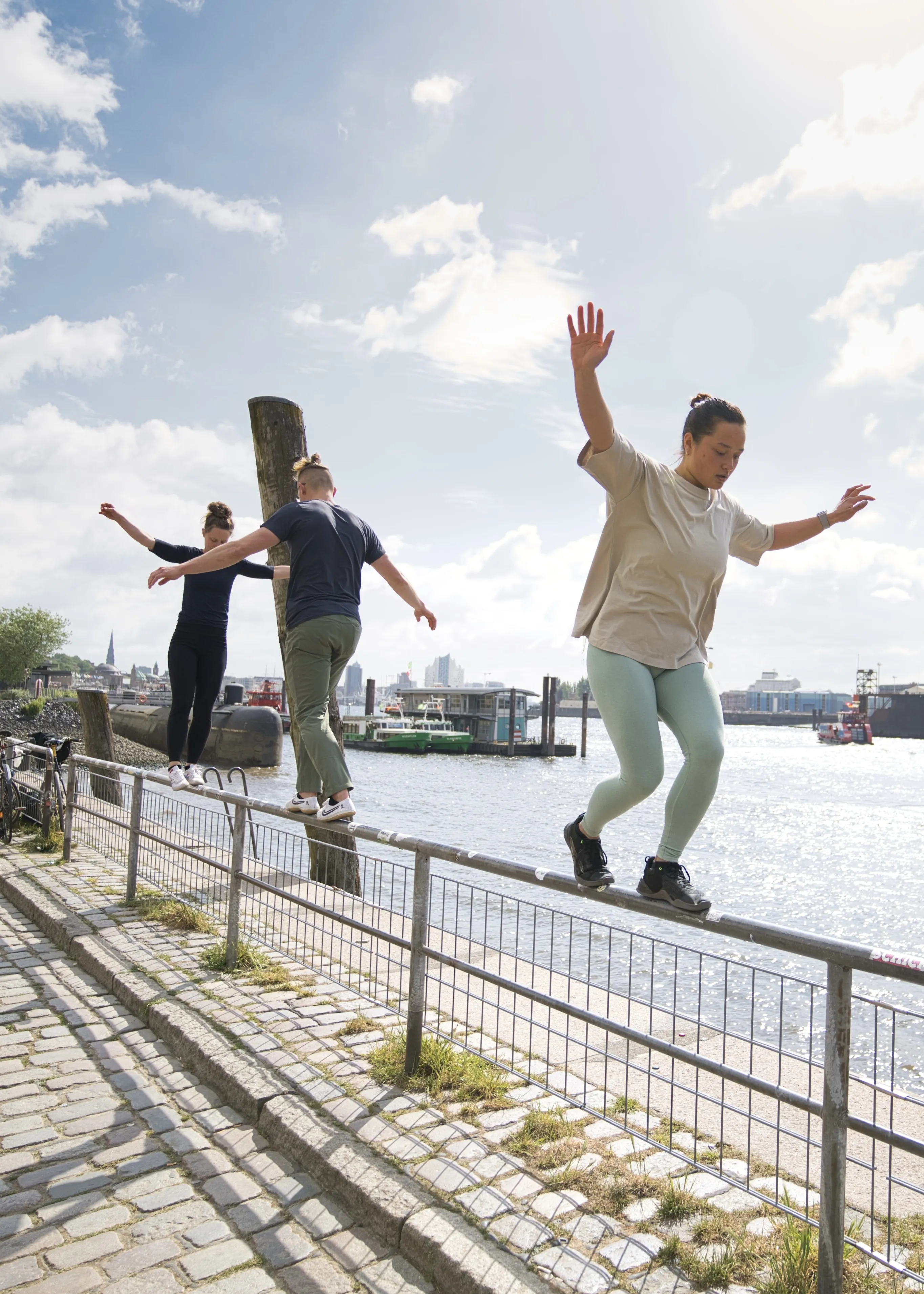 Drei Personen balancieren auf einem Geländer am Hamburger Hafen — School of Movement Outdoor-Training